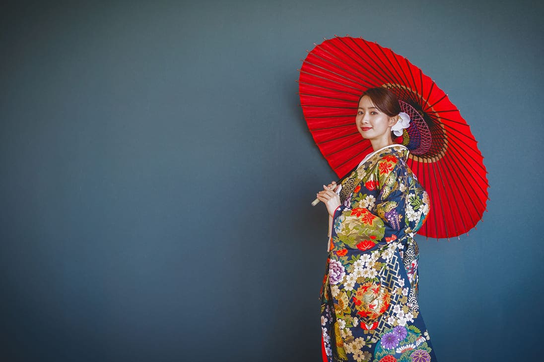 和装の新婦が和傘を持って笑っている
