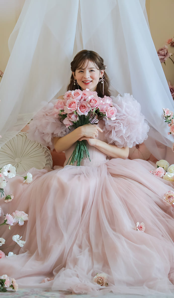 ピンクの花々に囲まれて微笑んでいる新婦