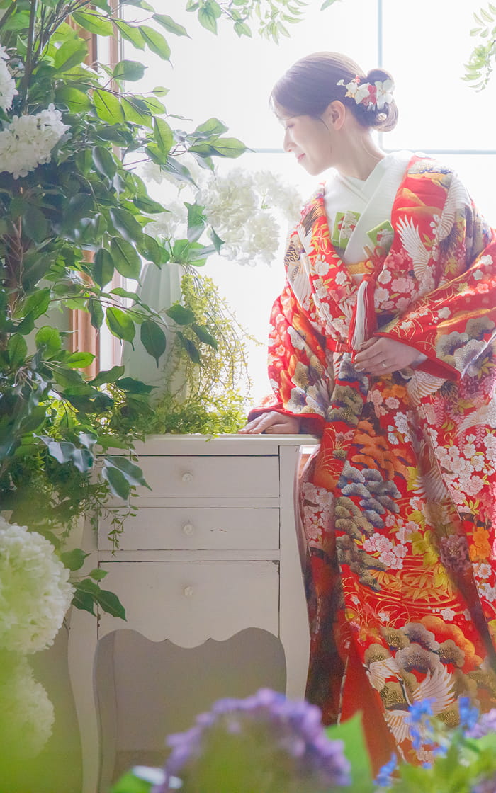 紫陽花に囲まれて、赤い和装に身を包む新婦