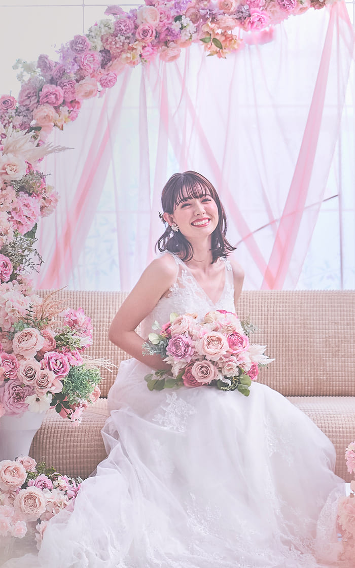 ピンクの花々に囲まれて微笑んでいる新婦
