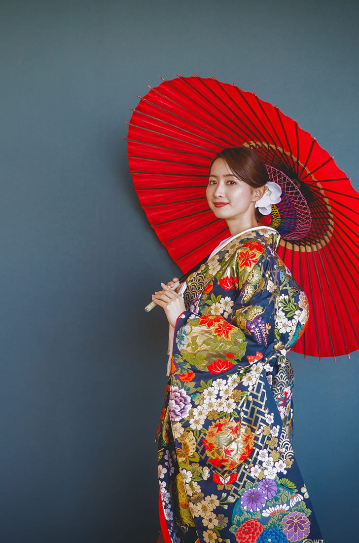 和装の新婦が和傘を持って微笑んでいる
